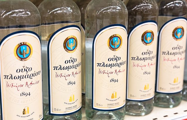Butelki kultowego greckiego ouzo, anyżowego destylatu z winogron, symbolu greckiego lata, często podawanego z wodą i lodem.