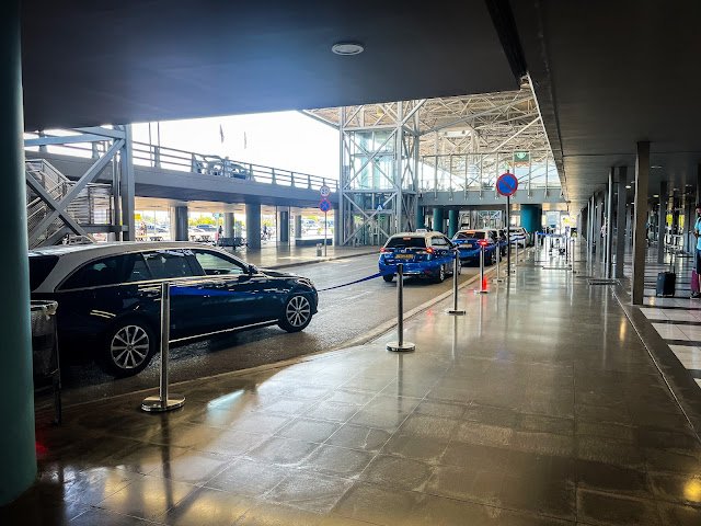 Taksówki czekające przed terminalem Międzynarodowego Lotniska Makedonia w Salonikach, gotowe do transportu turystów na Półwysep Chalcydycki.