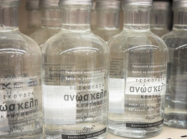 Przezroczyste butelki greckiego destylatu Tsipouro lub Tsikoudia, mocnego alkoholu z wytłoków winogron, popularnego w całej Grecji.